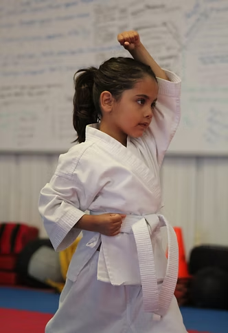 A young girl is practicing karate in a gym.