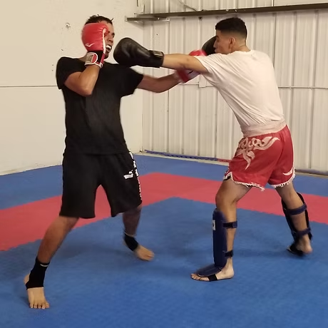Two men are boxing on a mat with one wearing shorts with a dragon on them
