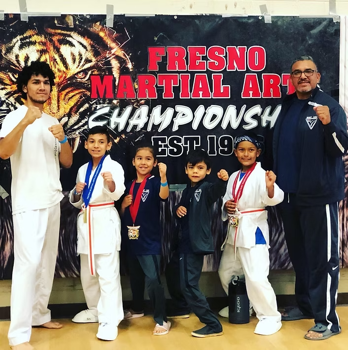 A group of kids standing in front of a fresno martial arts championship banner