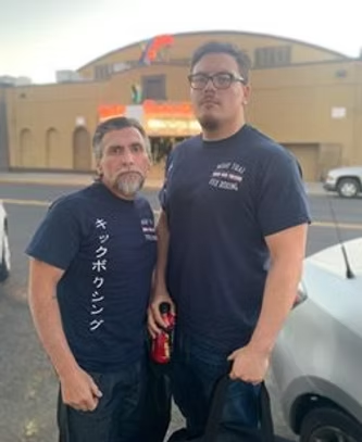Two men standing next to each other with one wearing a shirt that says kickboxing