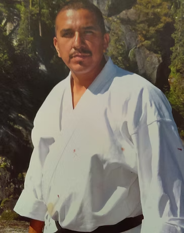 A man in a white karate uniform with a black belt
