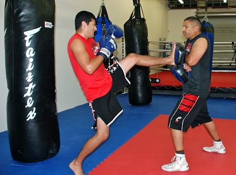 Two men kickboxing in front of a warrior bag