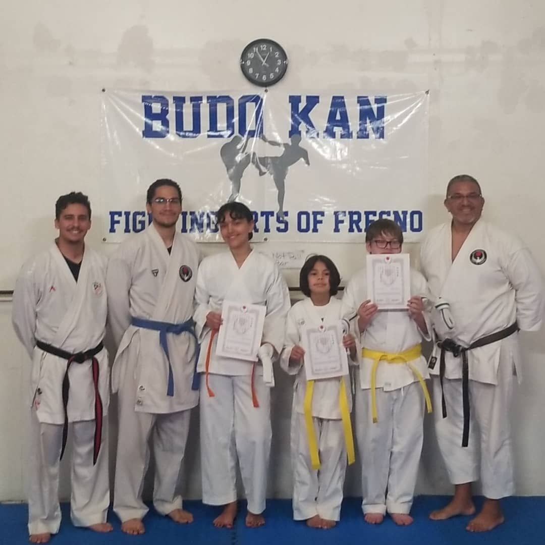 A group of people standing in front of a sign that says budo kan