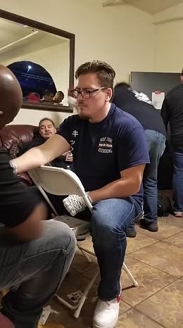 A man is sitting in a chair talking to another man.