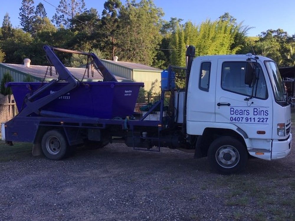 A White Garbage Truck With A Blue Dumpster Attached — Bears Bins Skip Hire In Meridan Plains, QLD