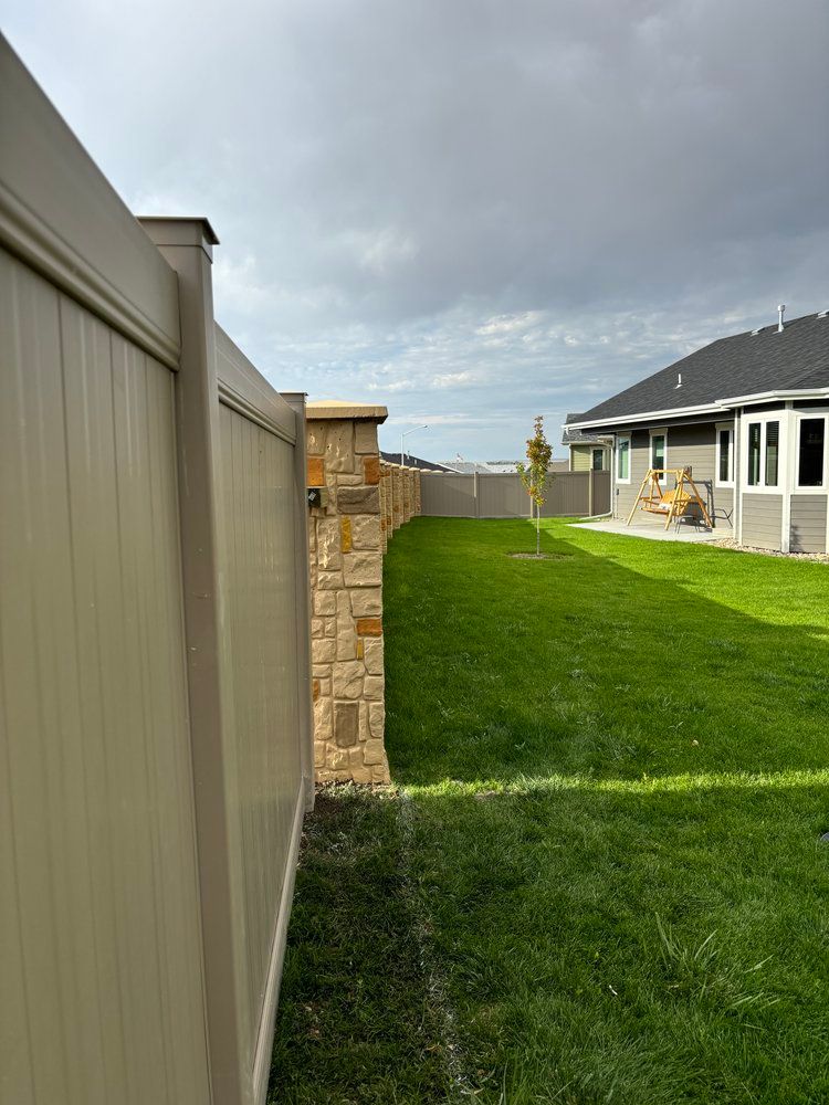A fence surrounds a lush green yard with a house in the background.