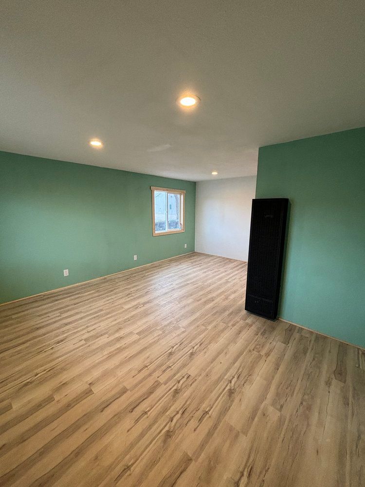 A large empty room with wooden floors and green walls.