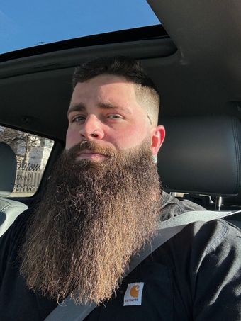 A man with a long beard is sitting in a car.