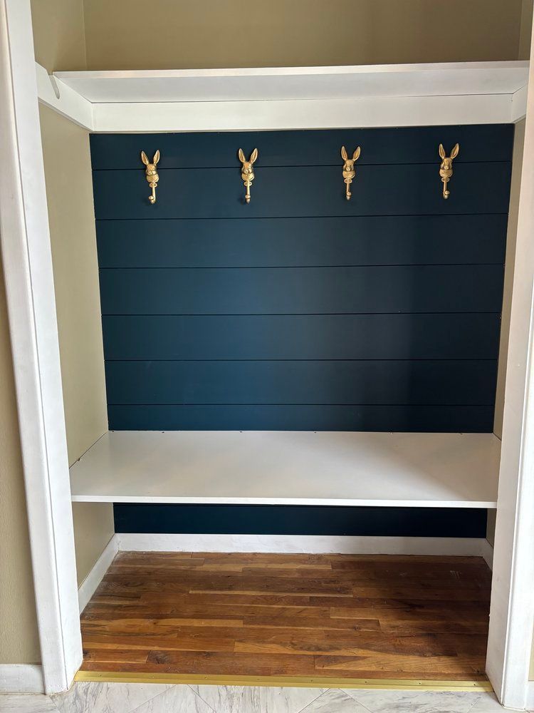 A closet with a shelf and hooks on the wall.