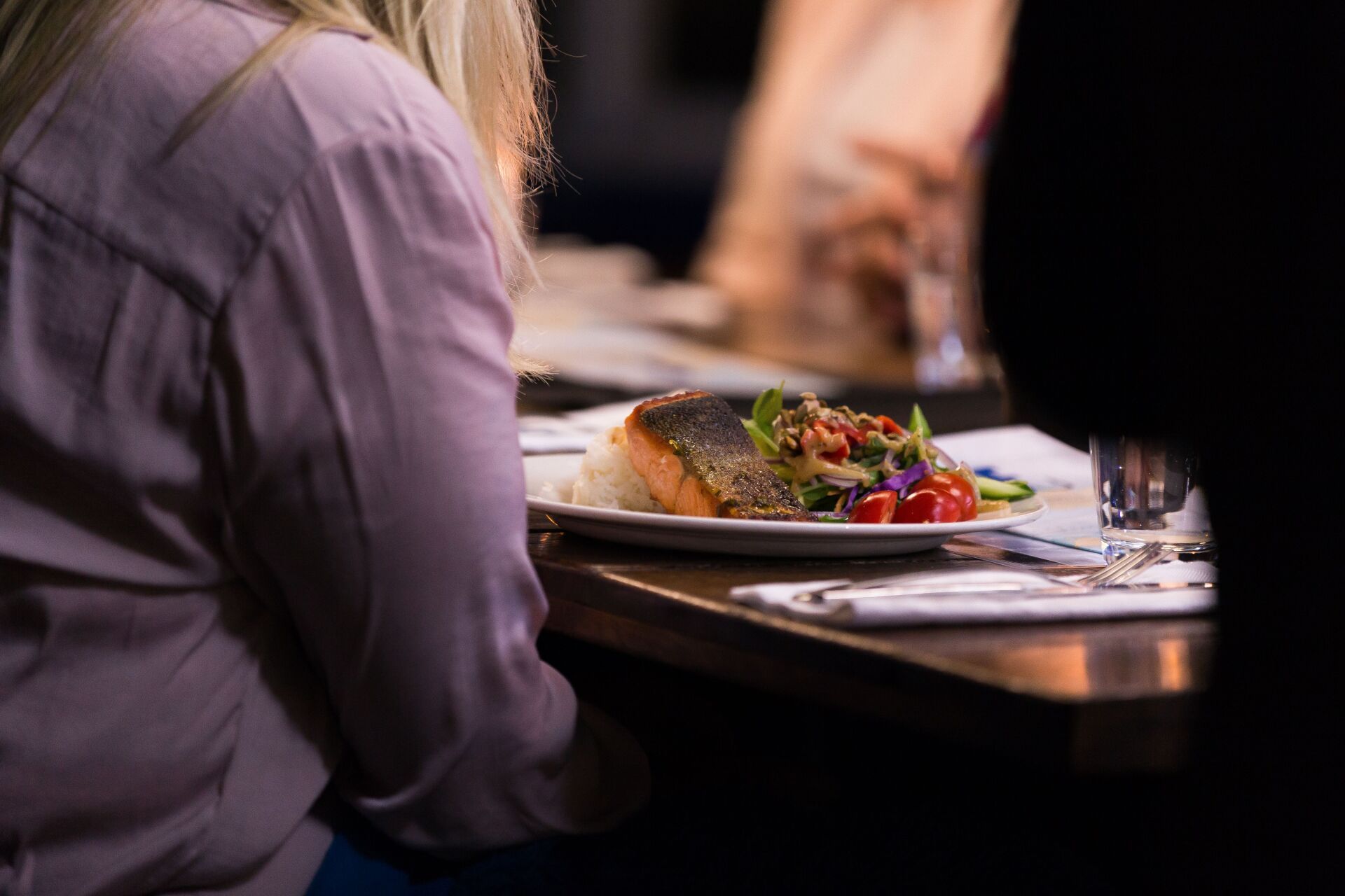 A woman is sitting at a table with a plate of food on it.
