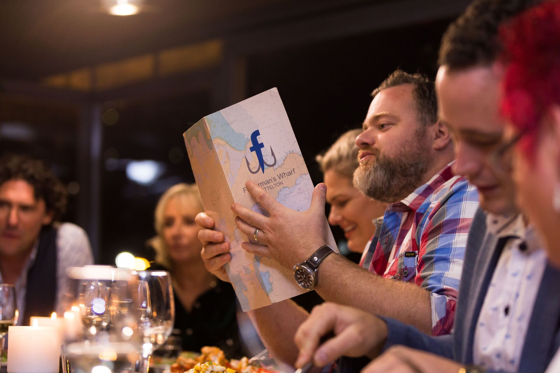 A group of people are sitting at a table eating food and drinking wine.