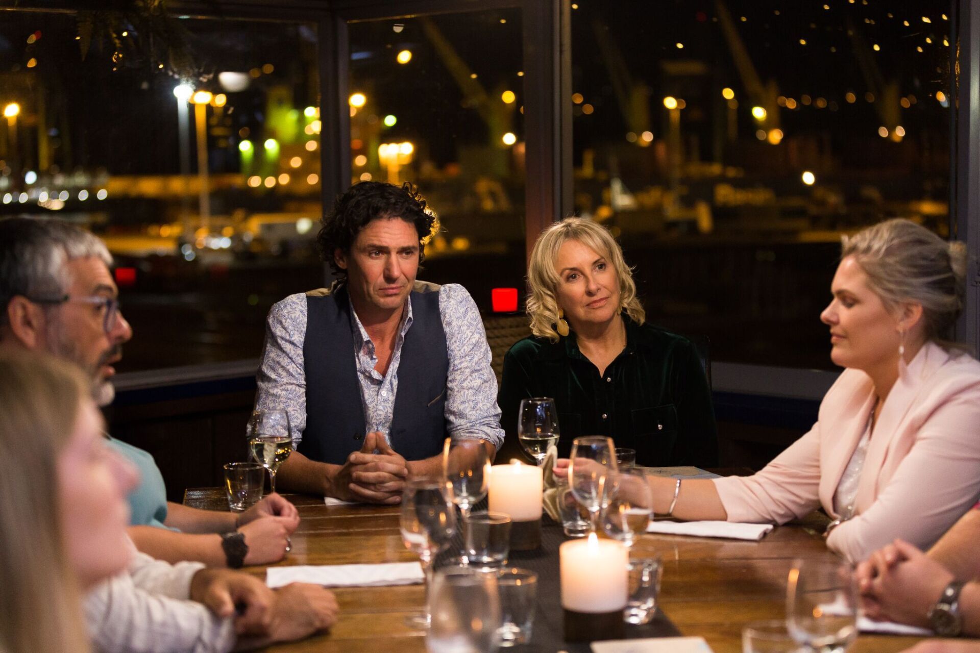 A group of people are sitting at a table with wine glasses and candles.