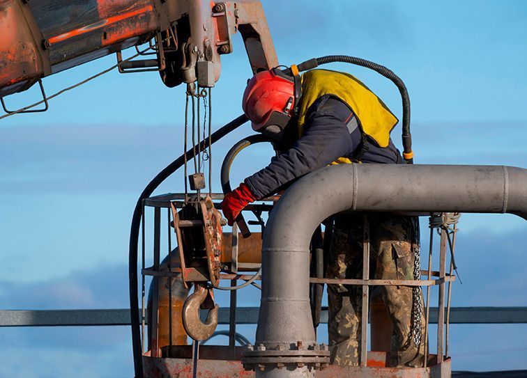 A man is working on a pipe with a crane.