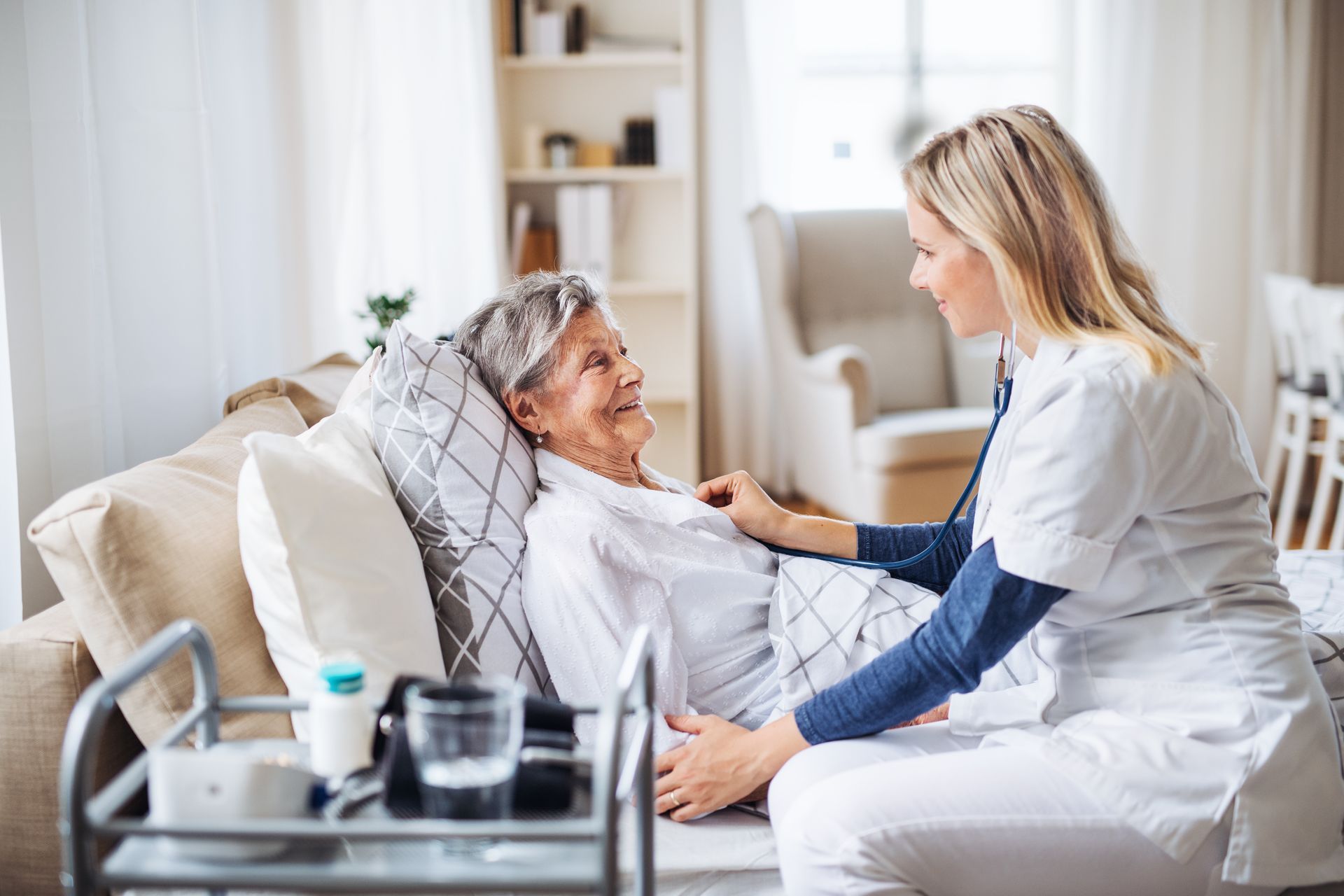 A nurse engages with an elderly woman in bed, delivering compassionate home health services.