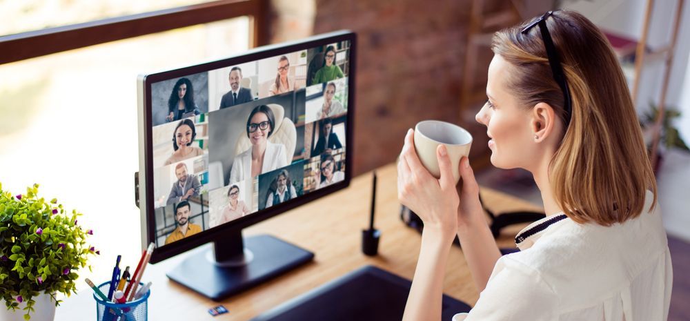 A woman is sitting in front of a computer holding a cup of coffee.