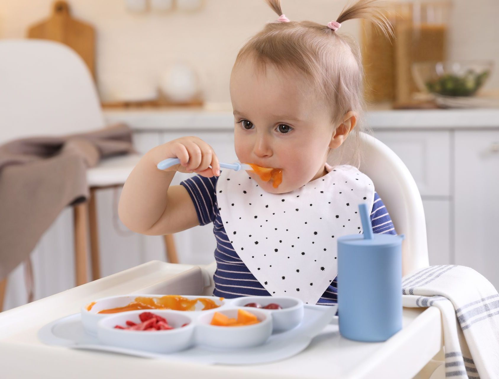 a baby is sitting in a high chair eating food with a spoon