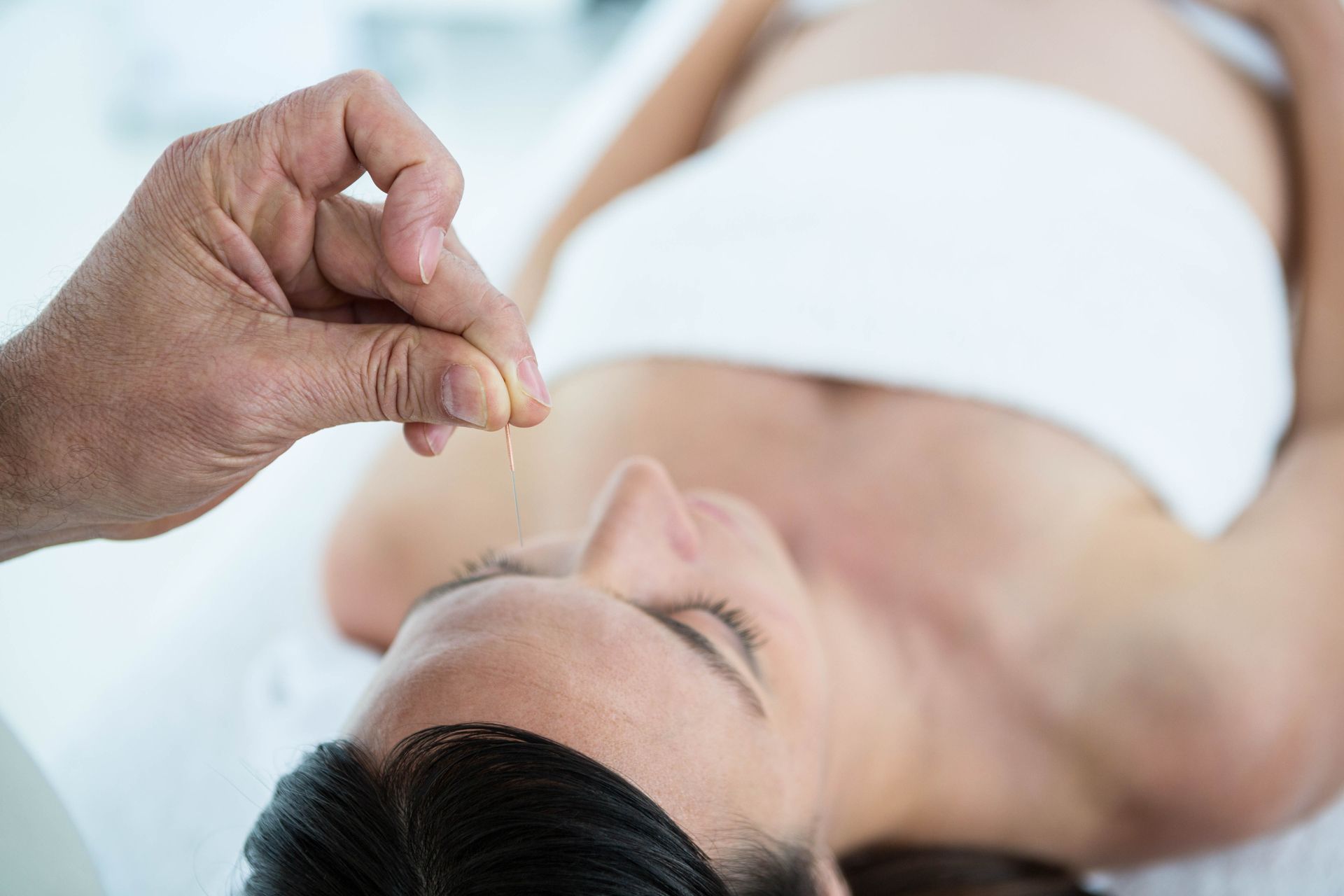 A pregnant woman is getting an acupuncture treatment at a spa.
