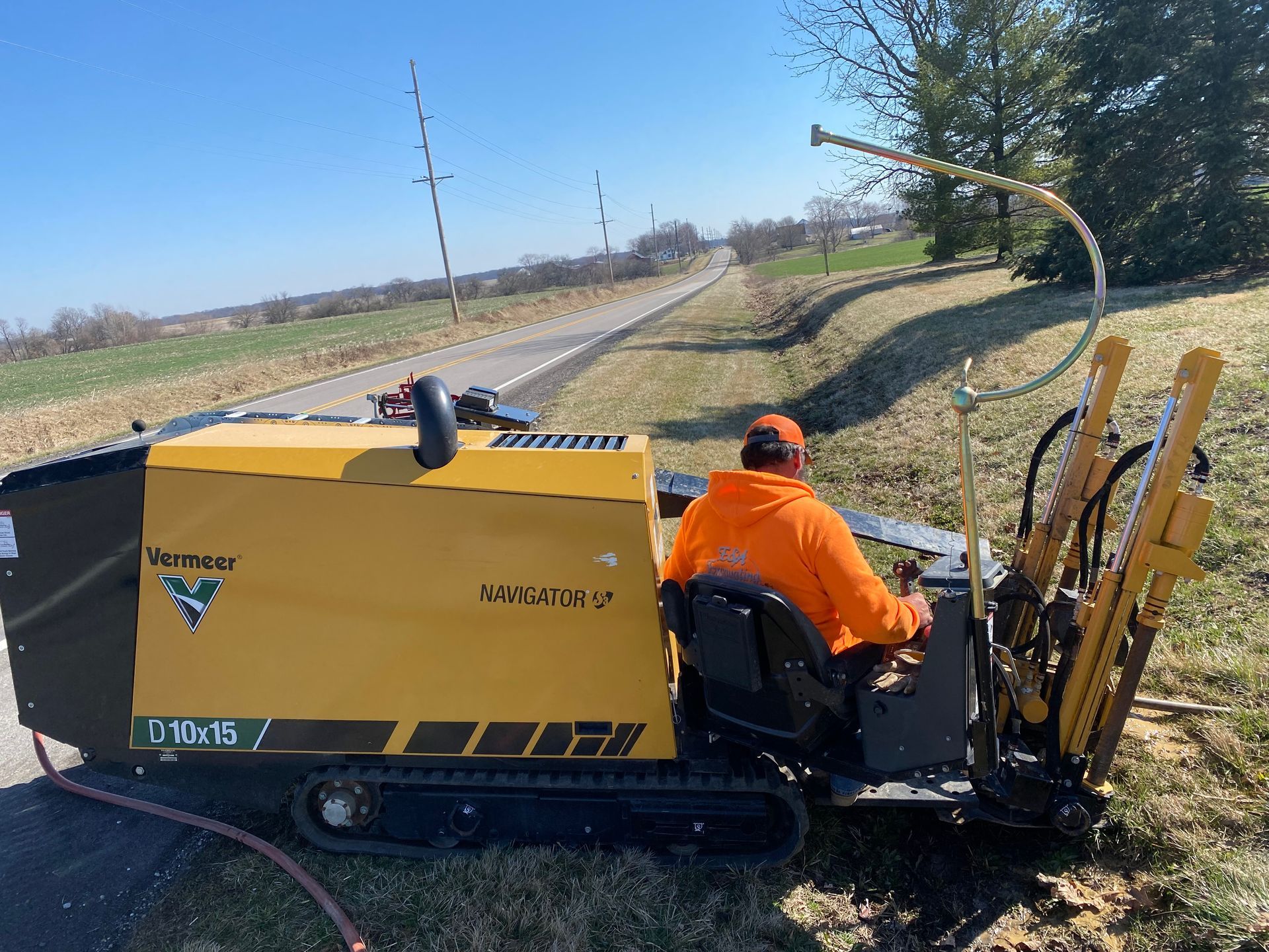 A man is driving a yellow and black machine on a dirt road.