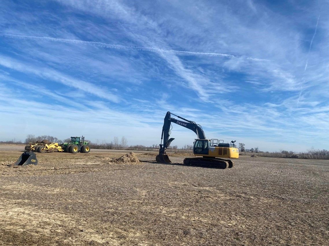 a large excavator is sitting in the middle of a field .