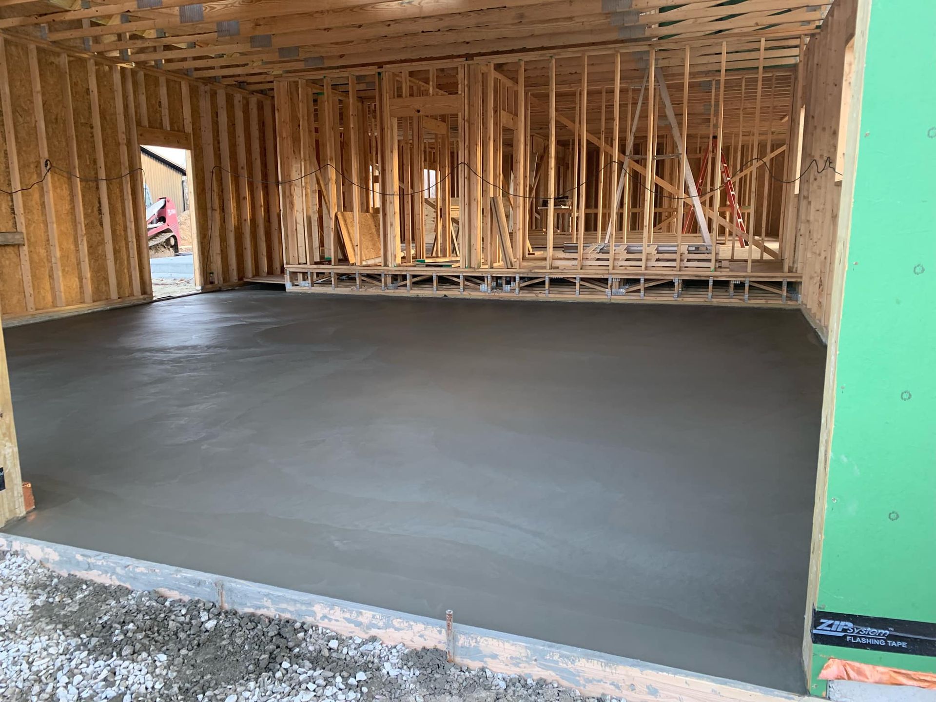 A concrete floor is being poured in a garage under construction.