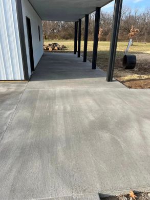 A concrete walkway leading to a building with a covered porch.
