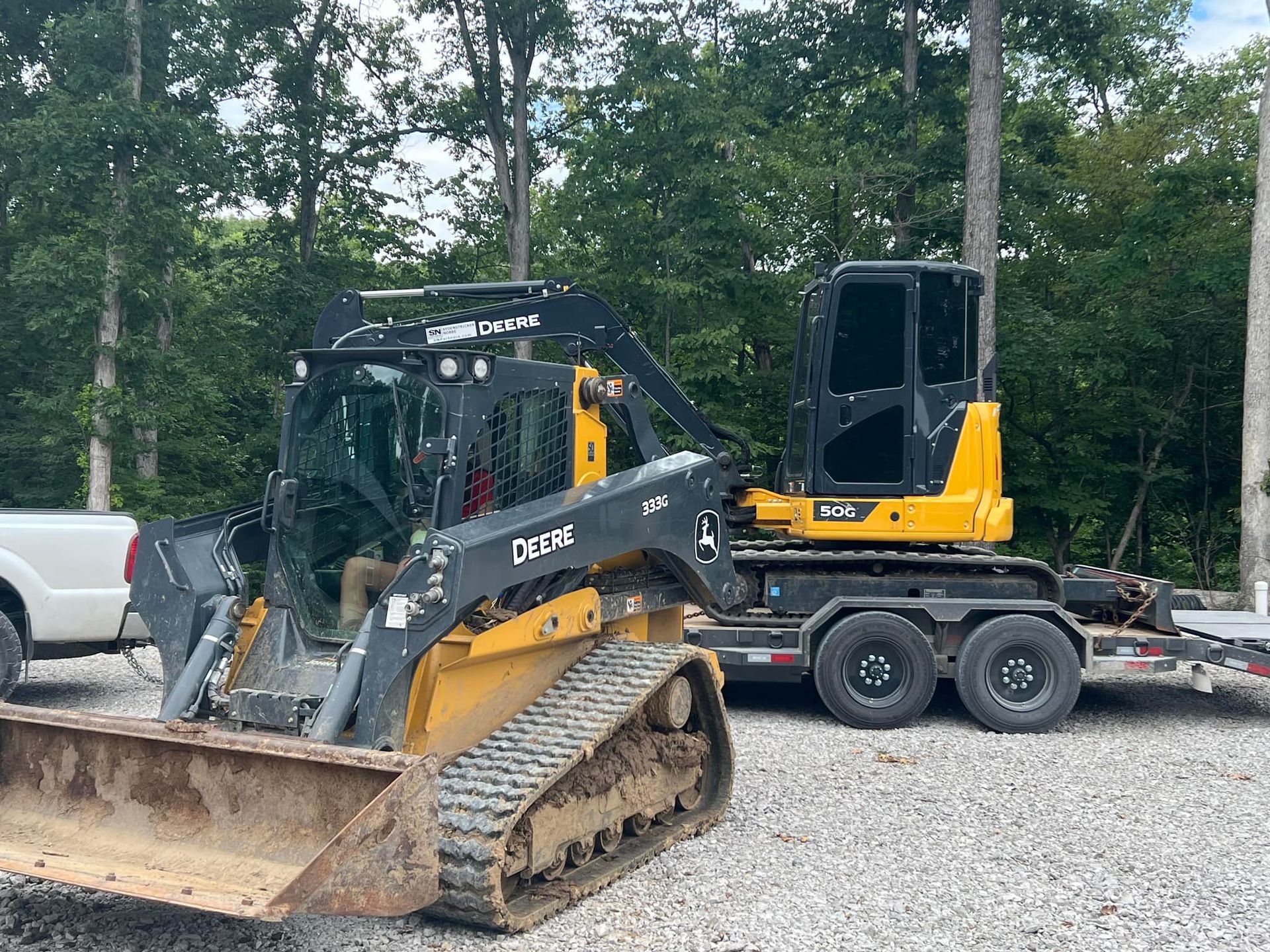 A bulldozer is parked next to a truck on a trailer.
