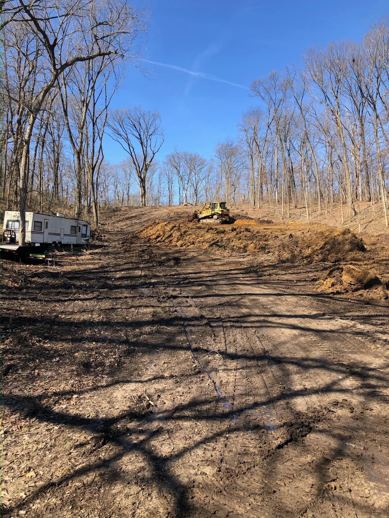 A rv is parked in the middle of a dirt road in the woods.