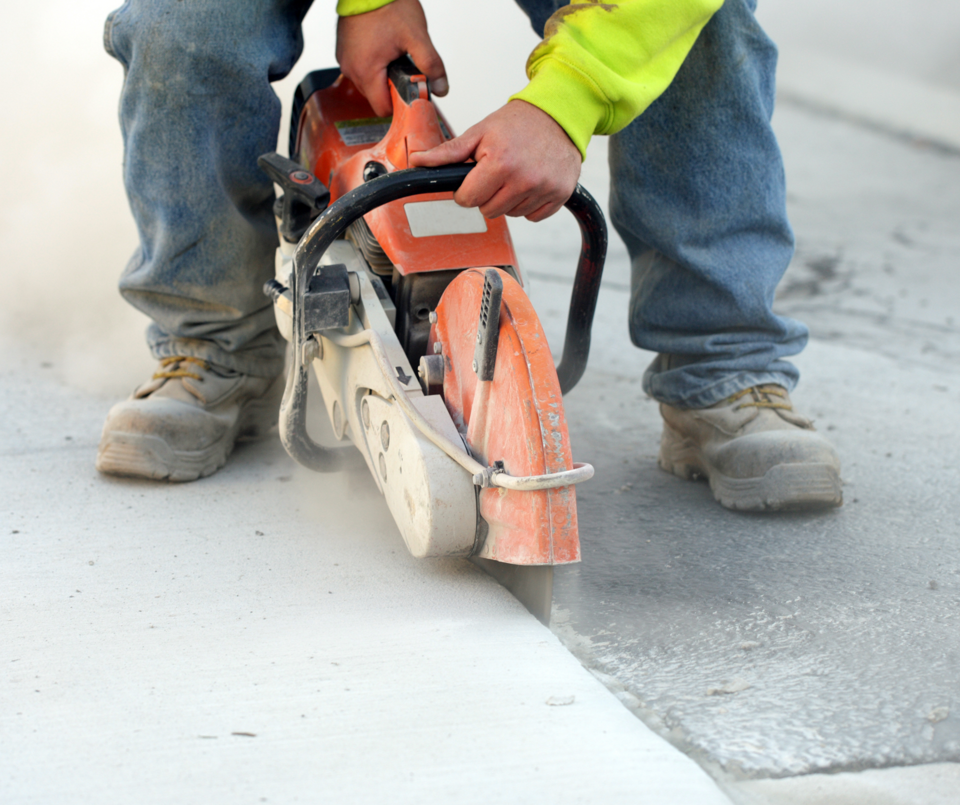 A man is using a chainsaw to cut a concrete curb