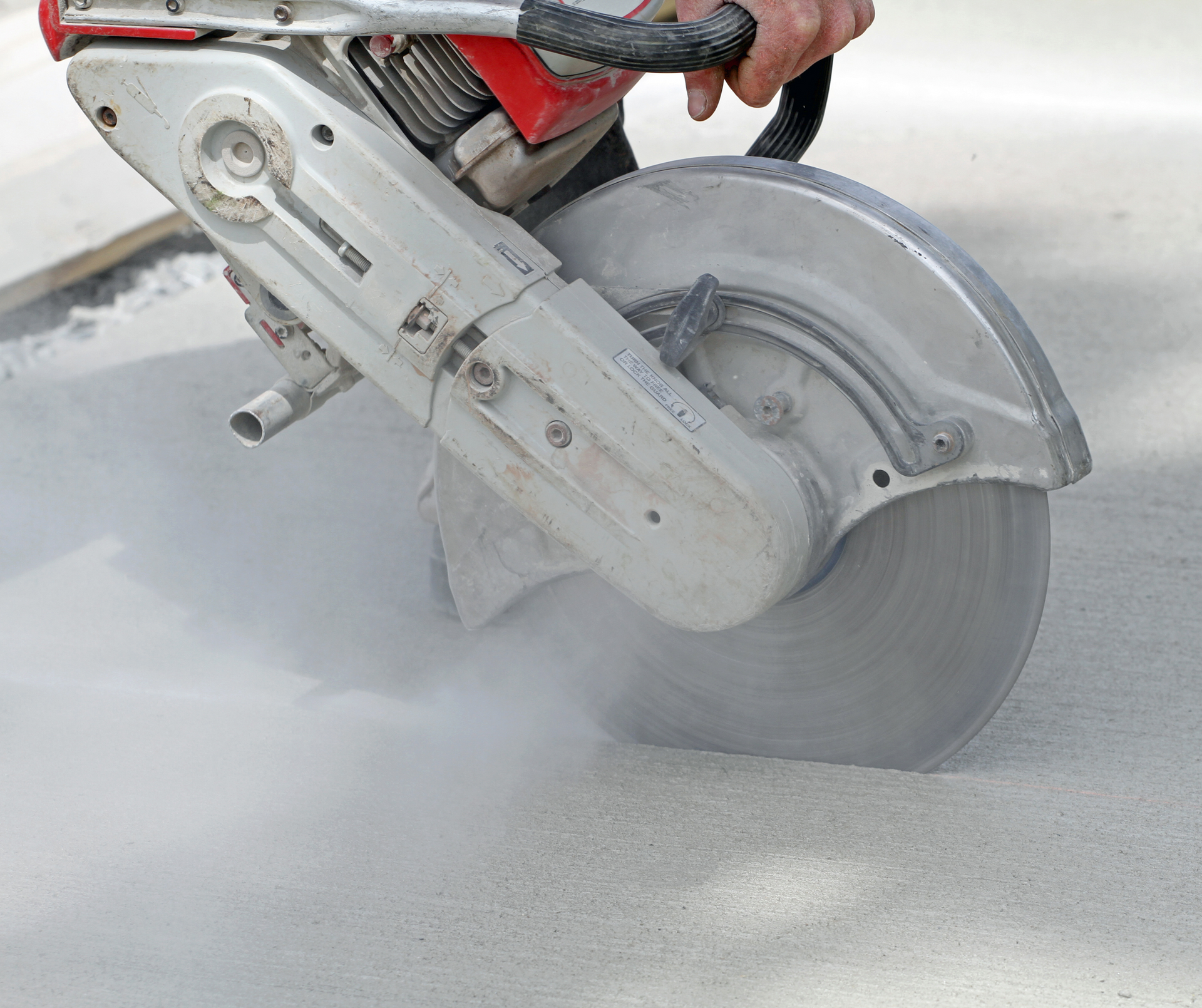 A person is using a circular saw to cut concrete