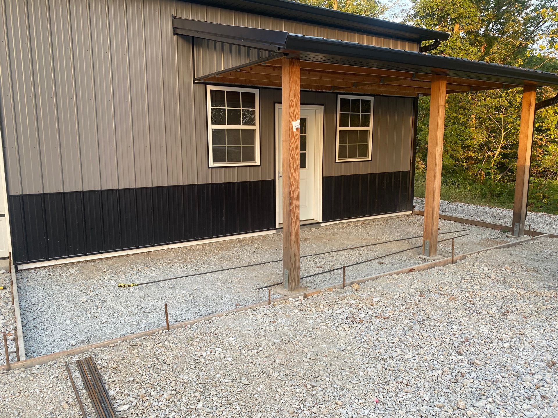 A house with a porch and a gravel driveway in front of it.