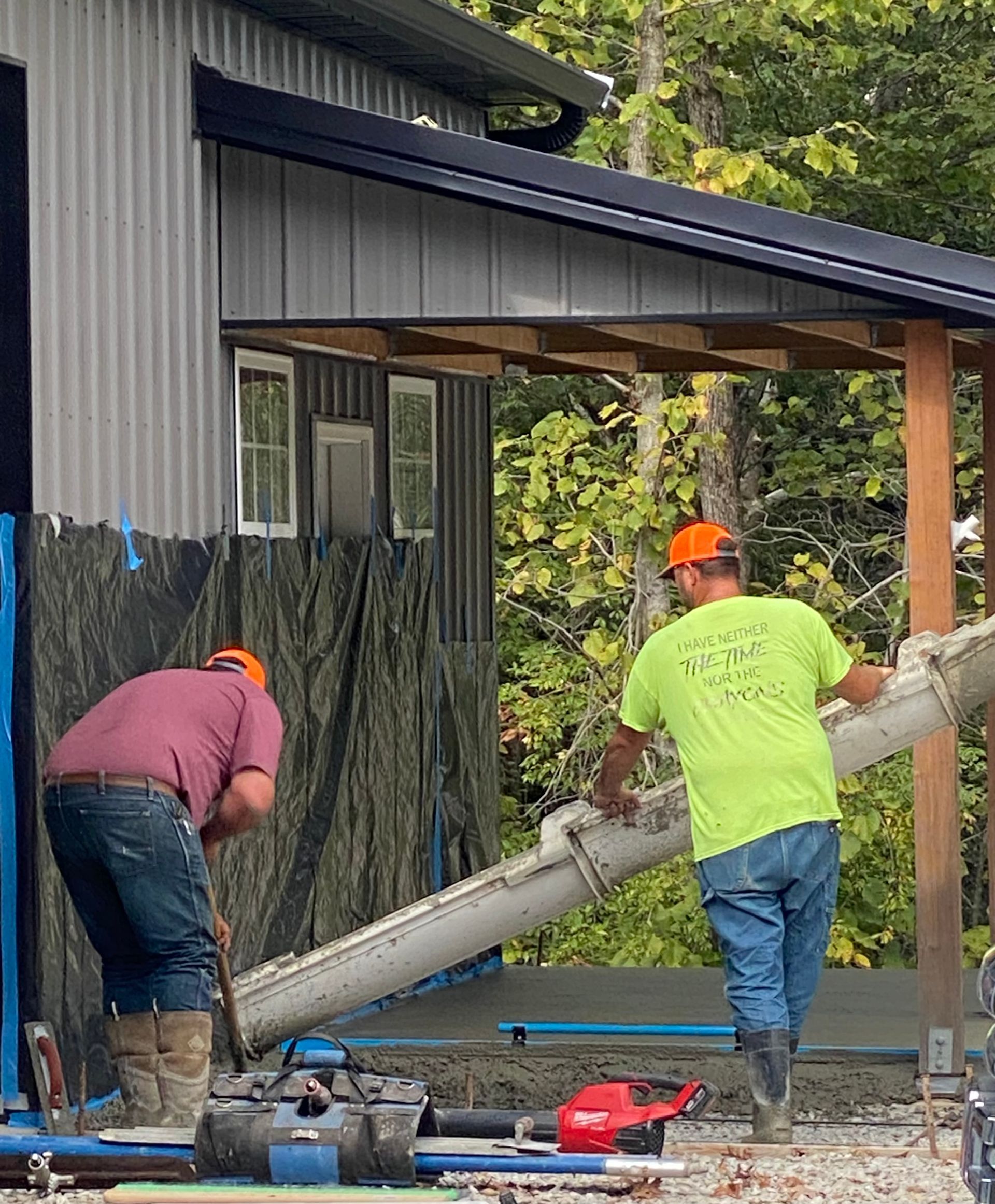 Two men are working on a construction site in front of a building.