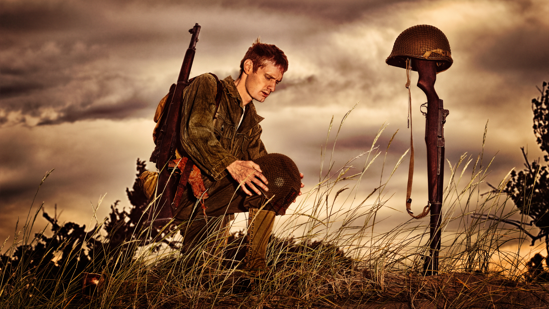 A soldier is kneeling in a field next to a grave.