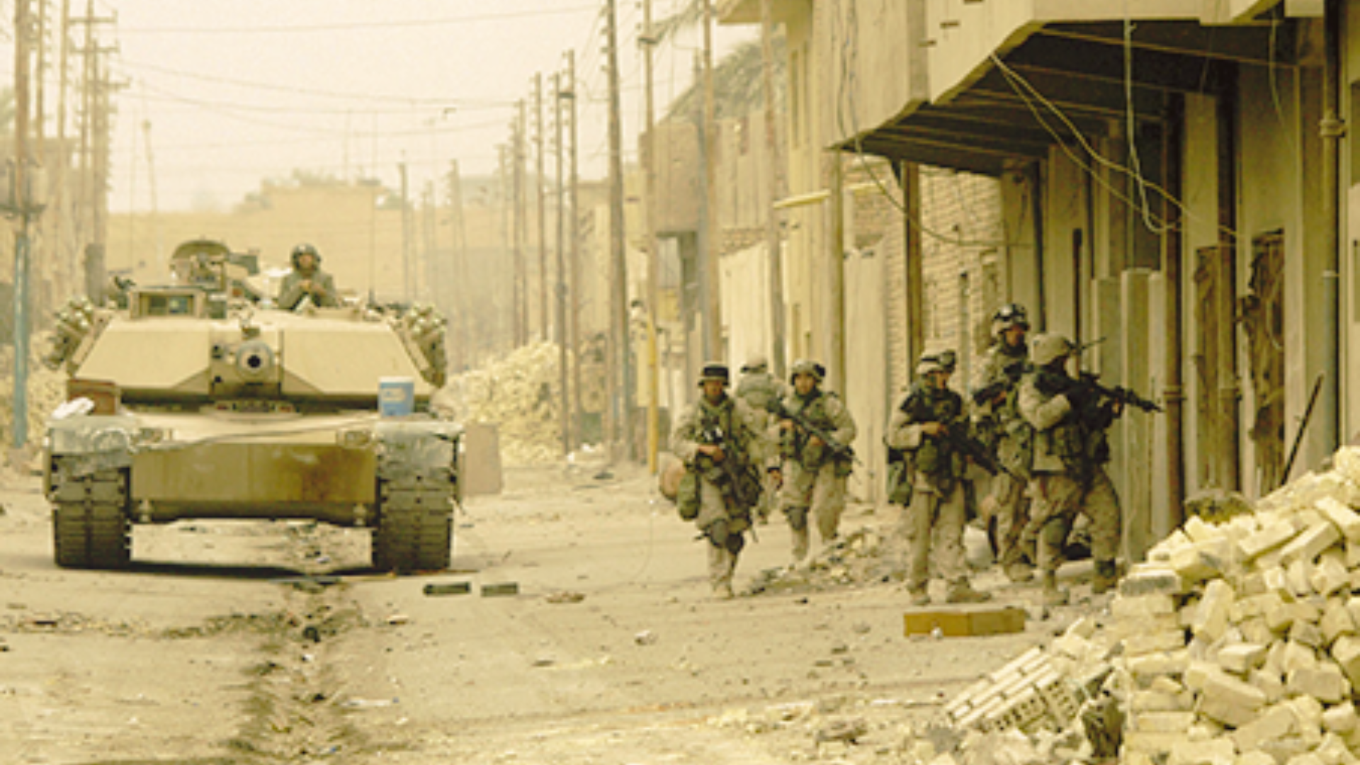 A group of soldiers are sitting in a trench looking at a fire.