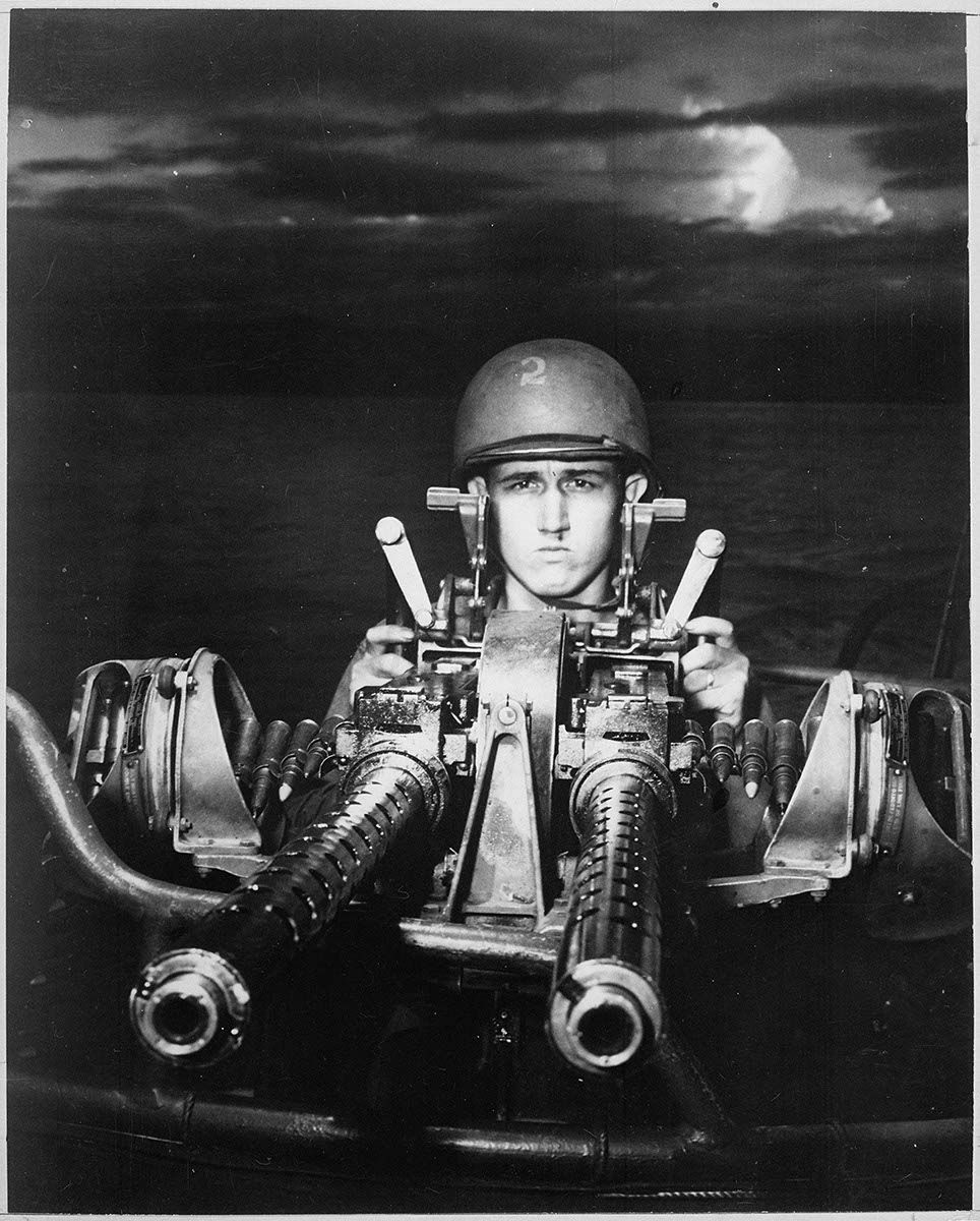 A black and white photo of a military convoy driving down a dirt road.