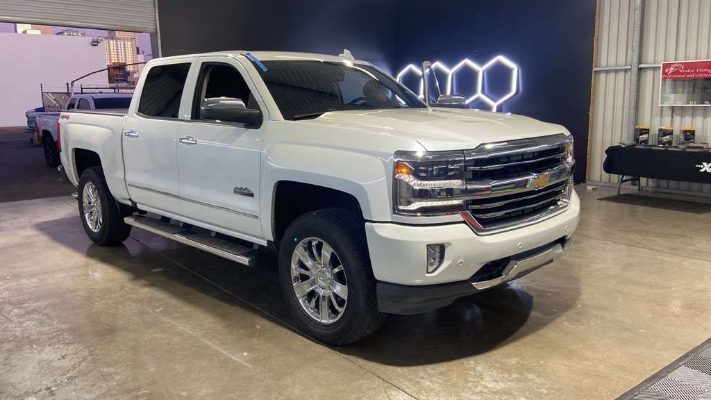 White Chevrolet pickup truck parked indoors, under bright lighting.