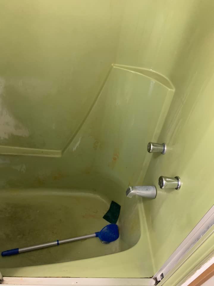A green bathtub with a blue brush in it.