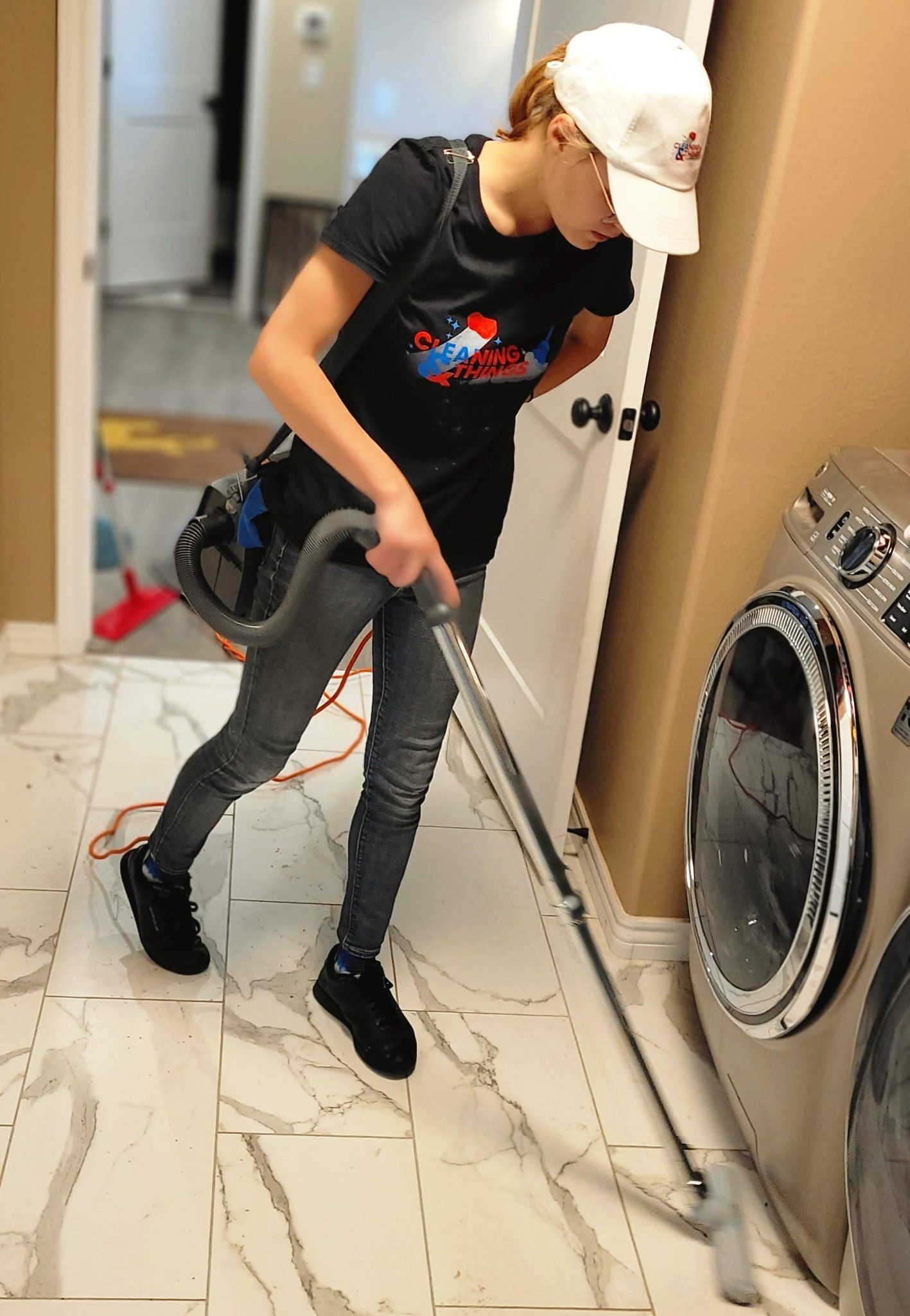 A woman is vacuuming the floor in a laundry room.
