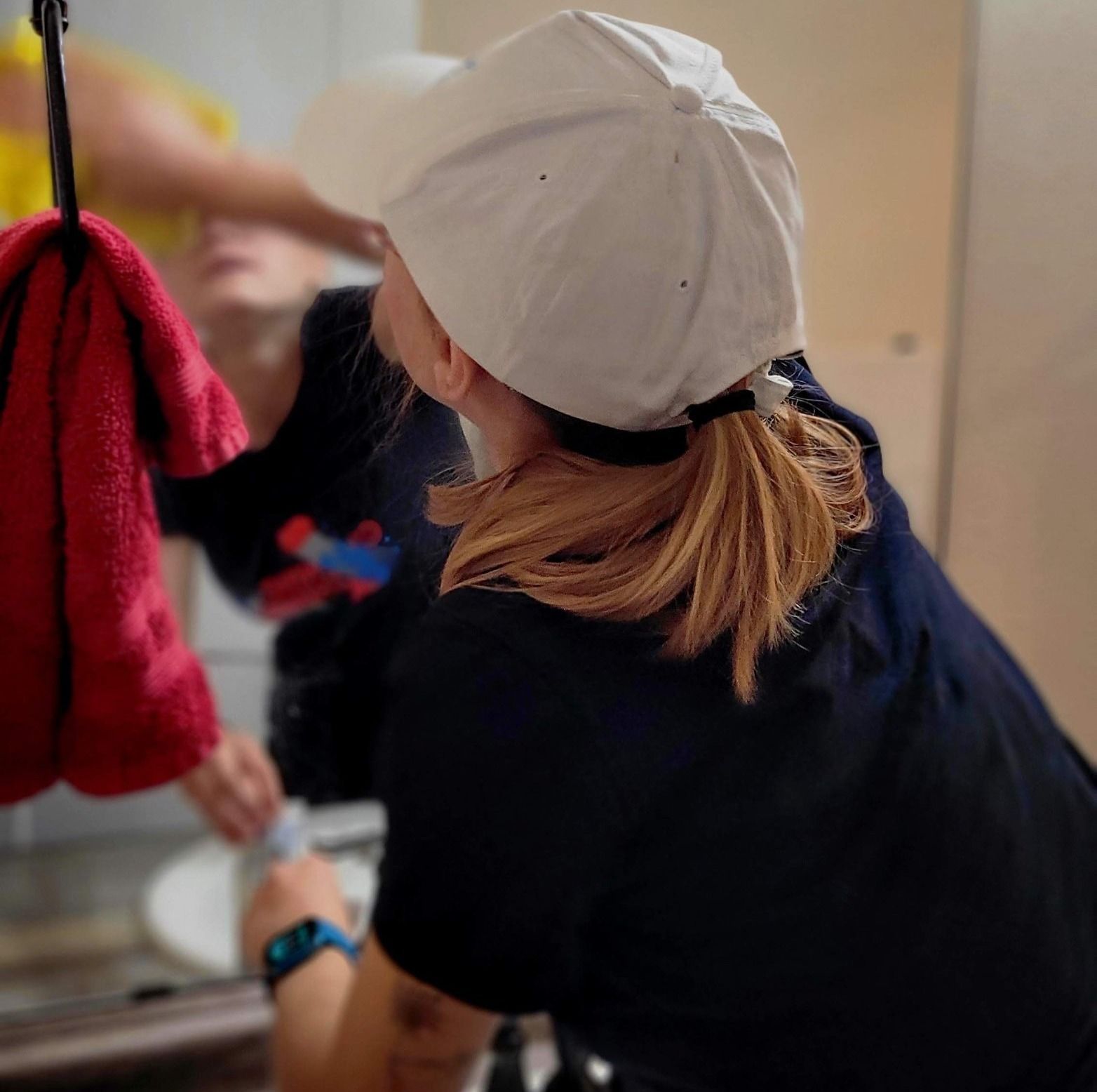 A woman in a baseball cap looks at her reflection in a mirror