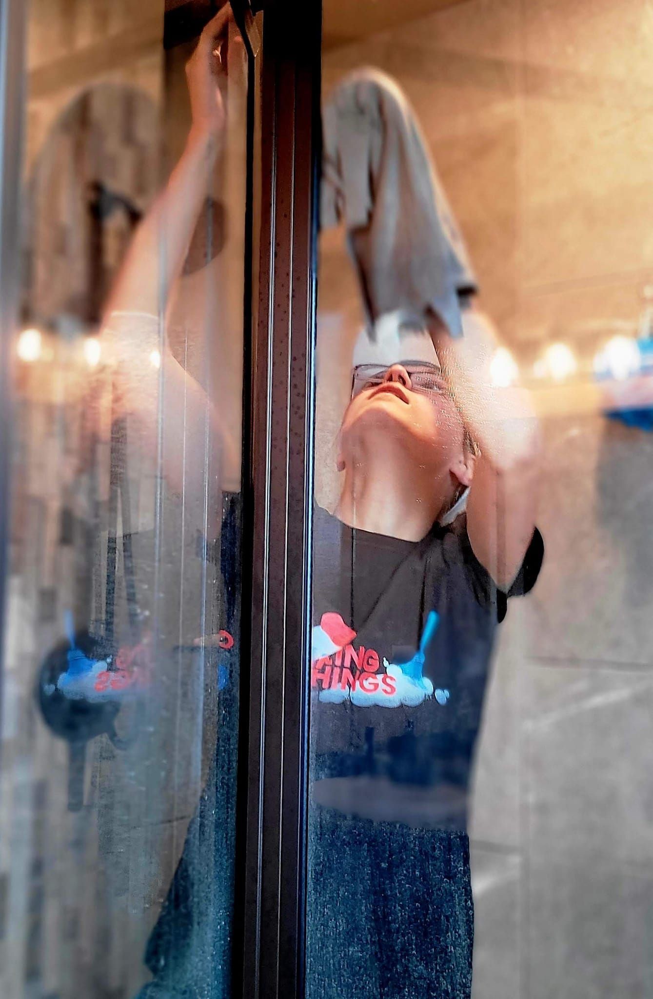 A person is cleaning a glass door with a towel.