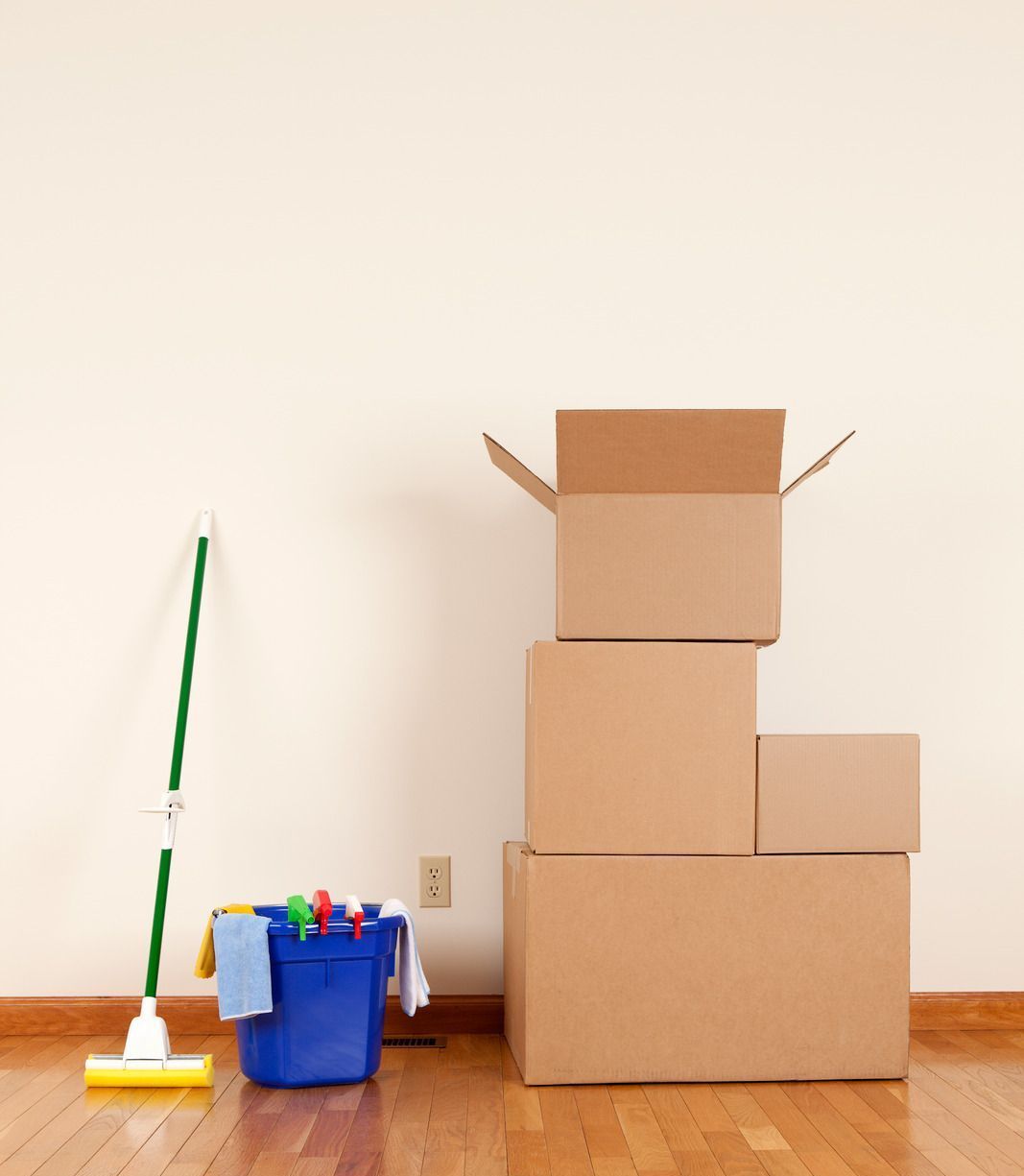 A stack of cardboard boxes next to a mop and bucket