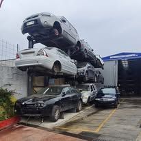 Auto impilate in un deposito di rottami, con i veicoli disposti su più livelli per lo stoccaggio e la lavorazione.