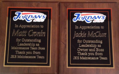 Two wooden award plaques from Jordan's honoring Matt Cronin and Jackie McClure for leadership from the JKS Maintenance Team.