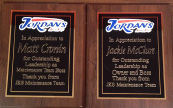Two wooden award plaques from Jordan's honoring Matt Cronin and Jackie McClure for leadership from the JKS Maintenance Team.