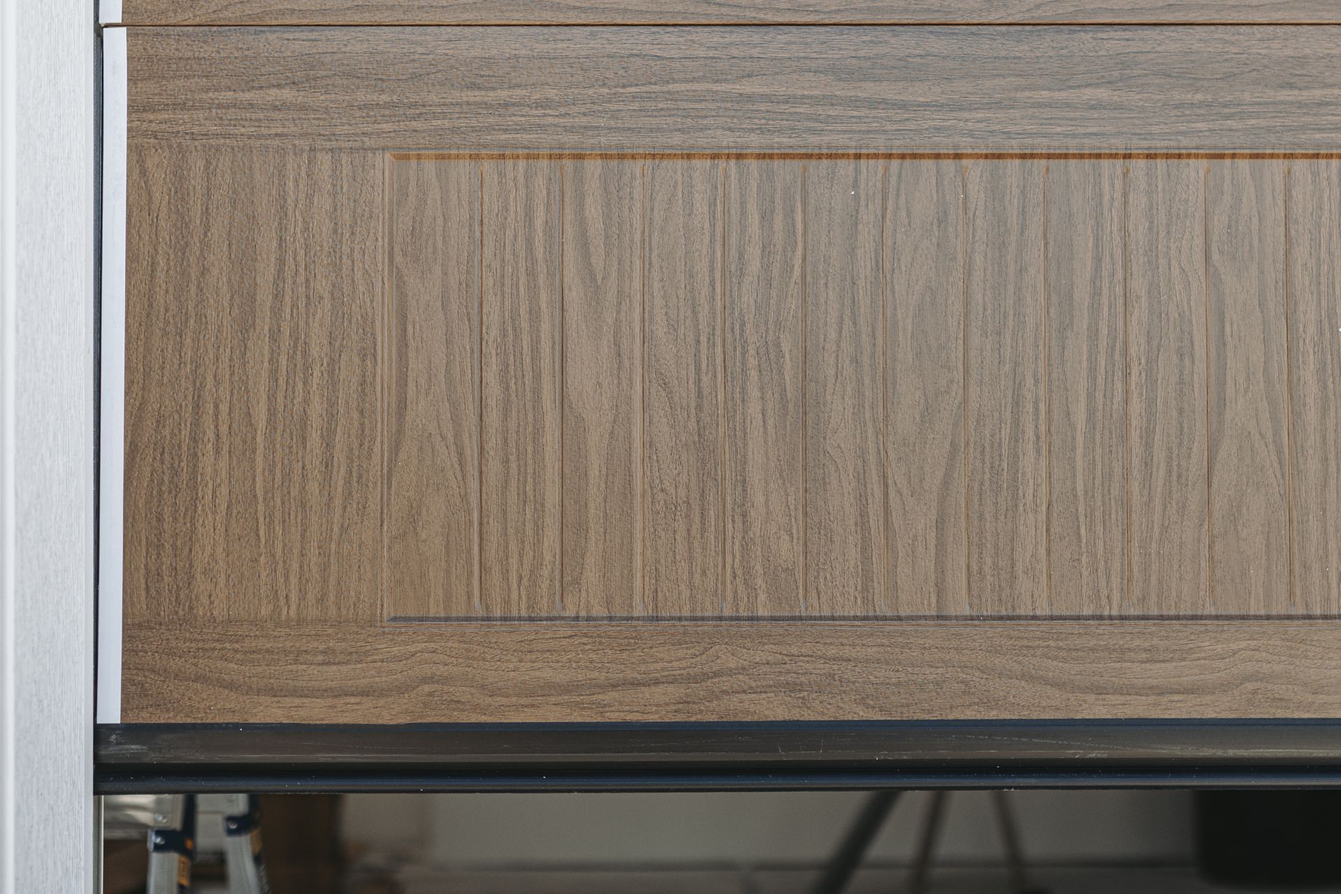 Close-up of a brown, textured cabinet door with a recessed panel, set against a silver frame.