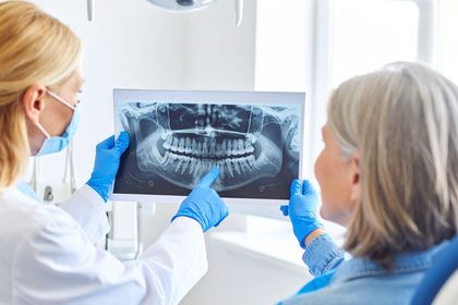 A dentist is looking at an x-ray of a patient 's teeth in Meridian, ID