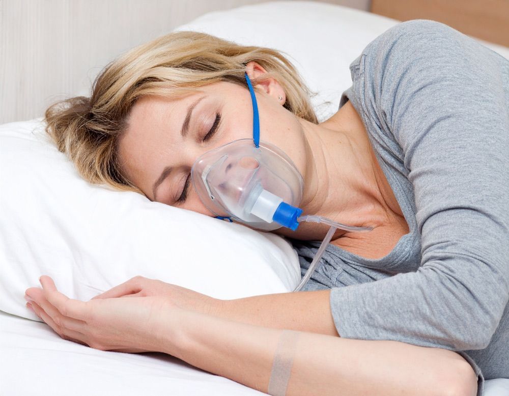 Woman sleeping in bed with an CPAP mask in Meridian, ID