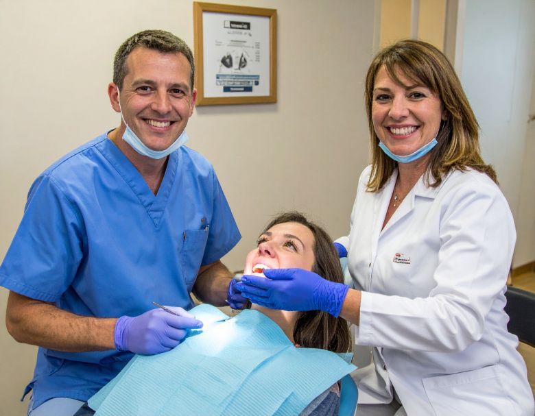Dentist and assistant examining a patient's teeth. All smiling in a dental office.