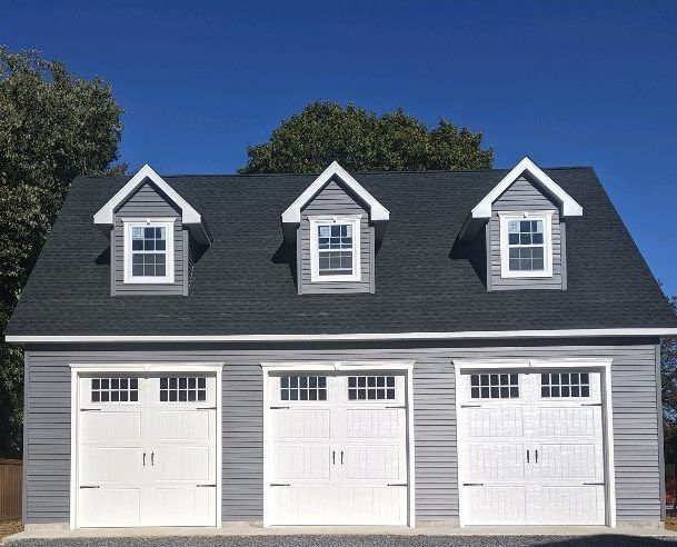 a garage with three white doors and a black roof