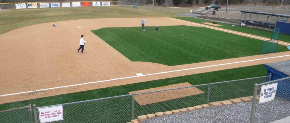 Baseball field with players on the field. A player is walking towards the bases on a sunny day.