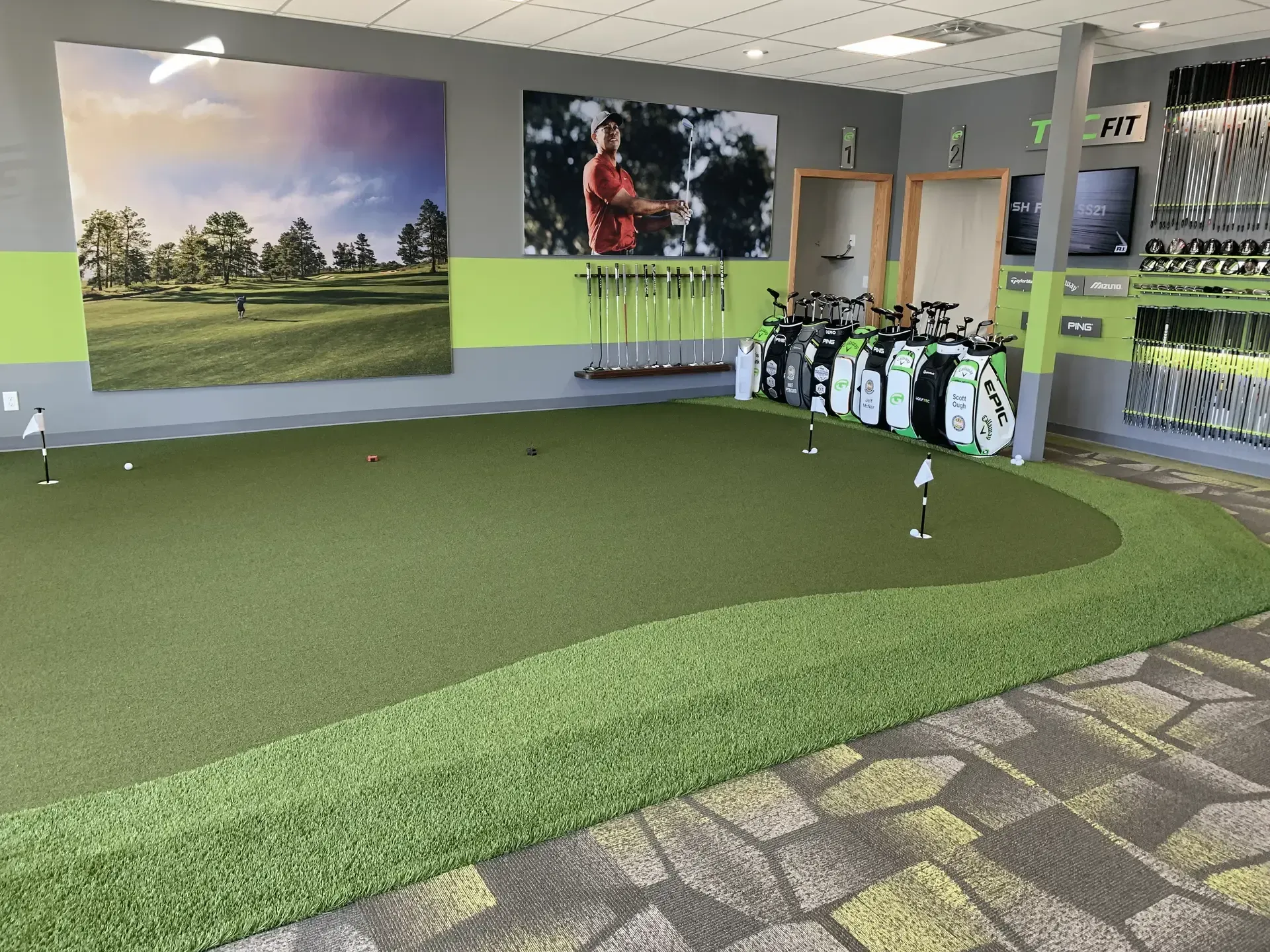 Indoor golf shop with a putting green, golf clubs, and wall art.